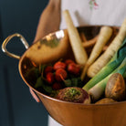 Person with white shirt on holding Galley and Fen Copper English tub filled with vegetables