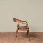 Ingrid Arm Chair in Teak against a beige background and brick floor