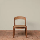 Ingrid Side Chair in Teak on a beige background and brick floor