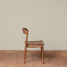 Ingrid Side Chair in Teak on a beige background and brick floor