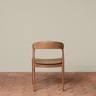 Ingrid Side Chair in Teak on a beige background and brick floor