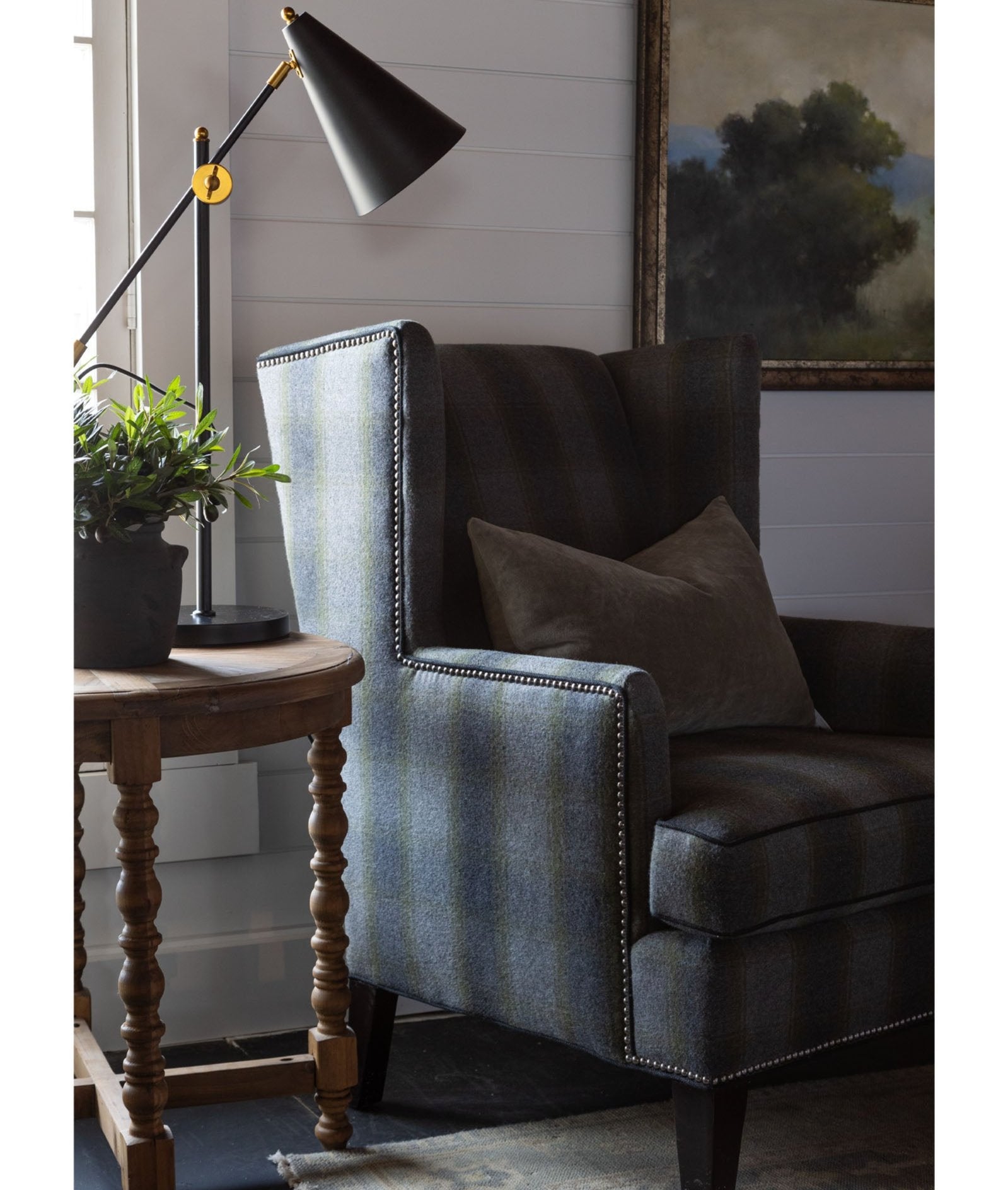 CR Laine Eliot Wingback Chair in Birkdale Moss plaid with muted landscape painting in the background 