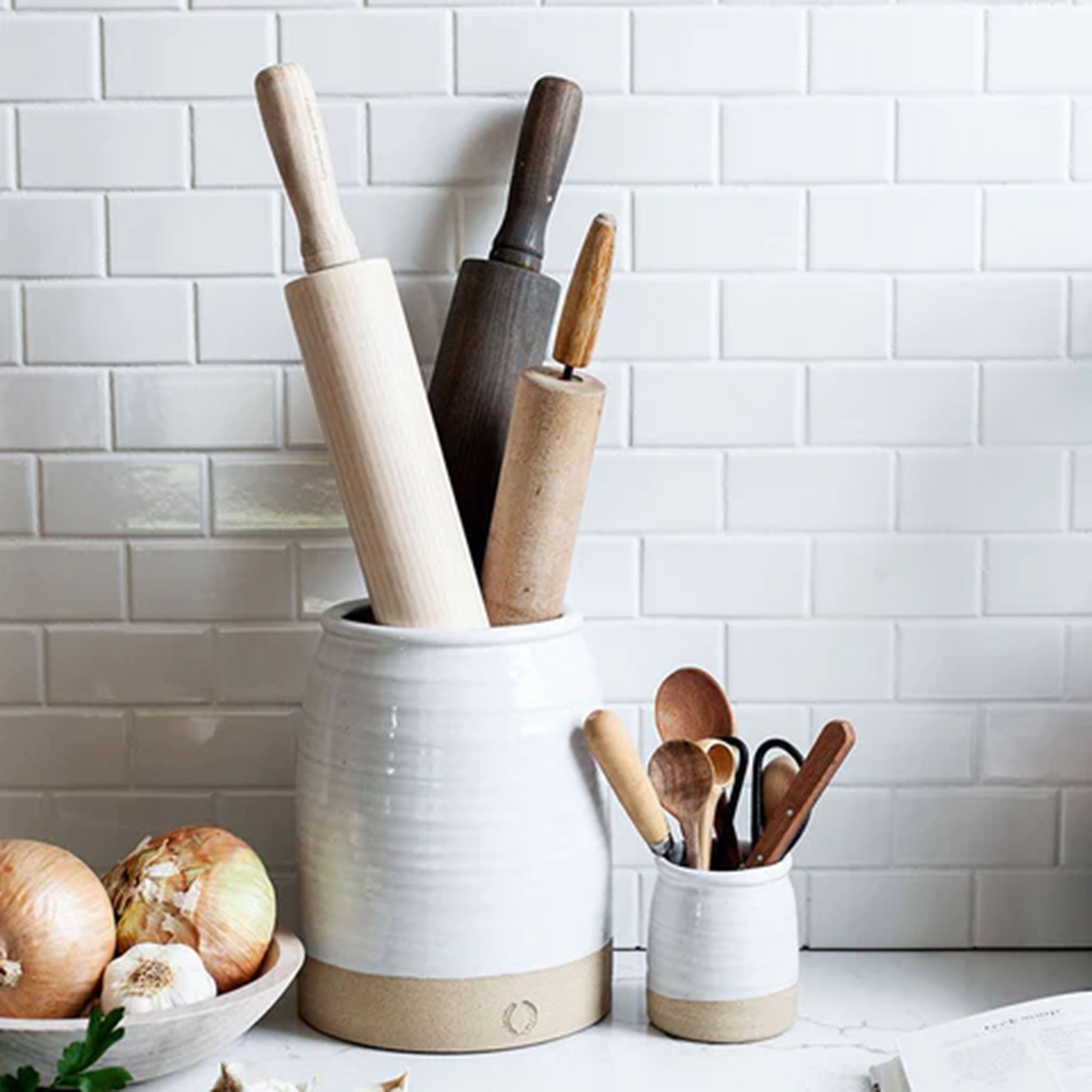 Farmhouse pottery beehive crocks on a white counter with subway tile backsplash 