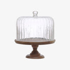 Wood cake stand with fluted glass dome on a white background