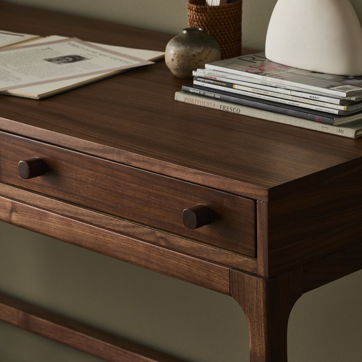 Close up of Four Hands Arturo Desk in Natural Walnut Veneer in a modern office with green walls