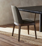 Four Hands Bryce Armless Dining Chair in Bilton Olive in a modern dining room with a black dining table