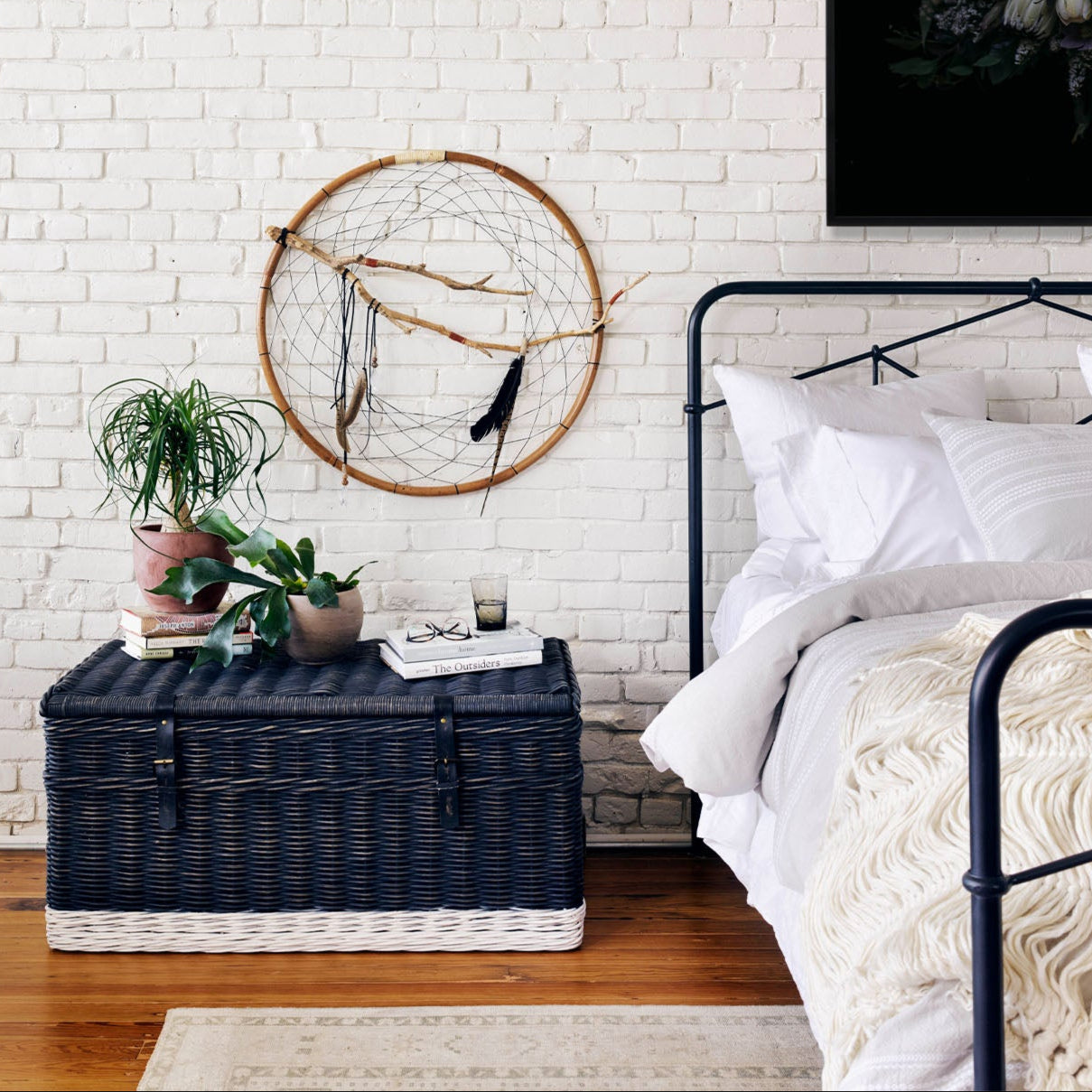 Four Hands Iron Casey Bed in Black in a room with wood floors and white painted brick