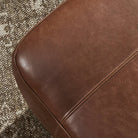 Close up of Four Hands Kylo Ottoman in Dulane Mahogany against a brown carpet at Addison West