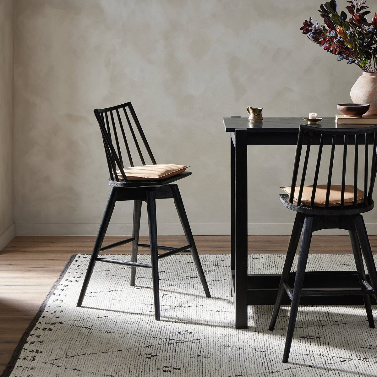 Four Hands Lewis Swivel Bar Stool in Whiskey Saddle at a black marble bar table at Addison West