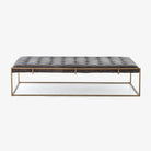 Four Hands oxford black leather tufted coffee table with brass frame on a white background