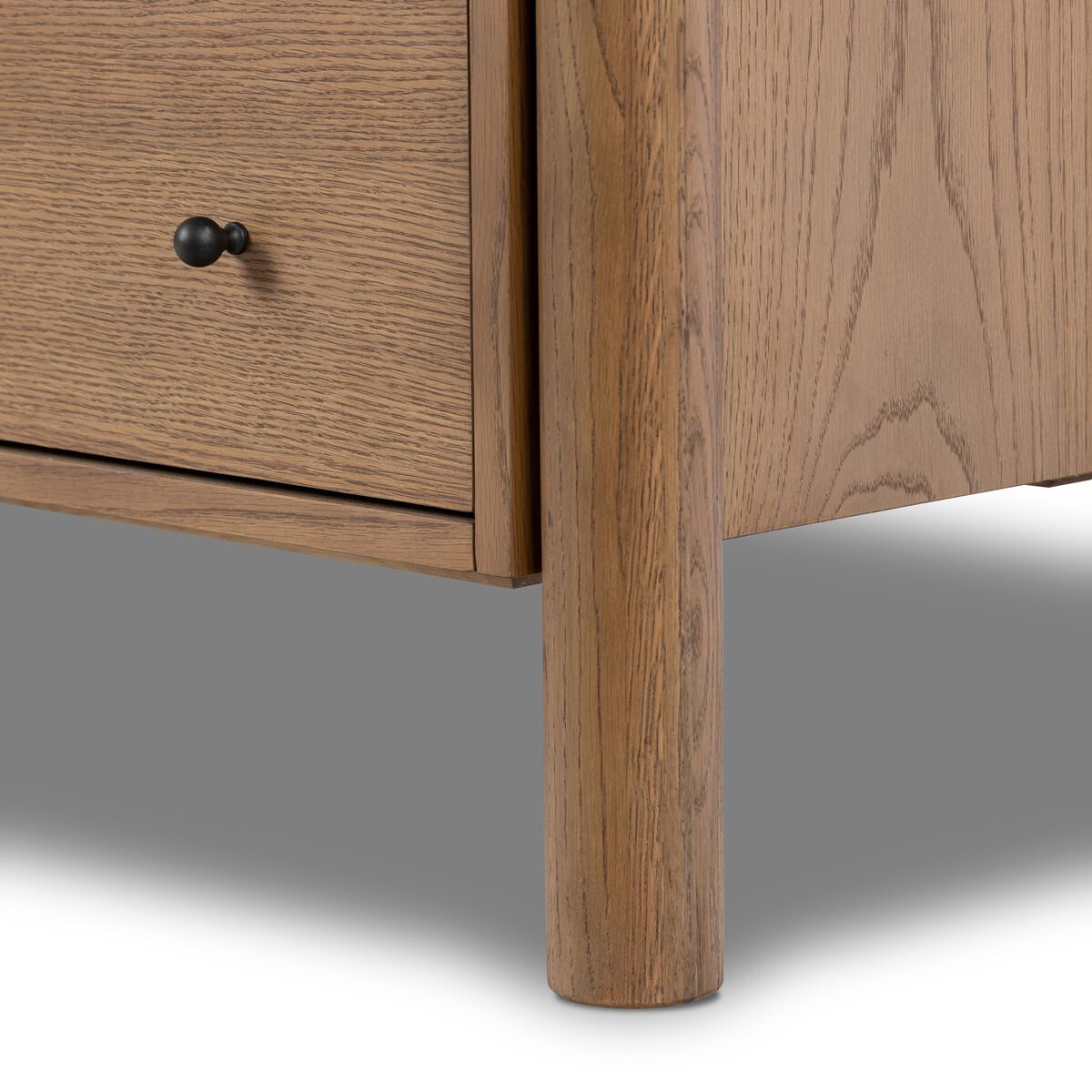 Close up of leg of Four Hands Roark 6 Drawer Dresser in Amber Oak Veneer on a white background