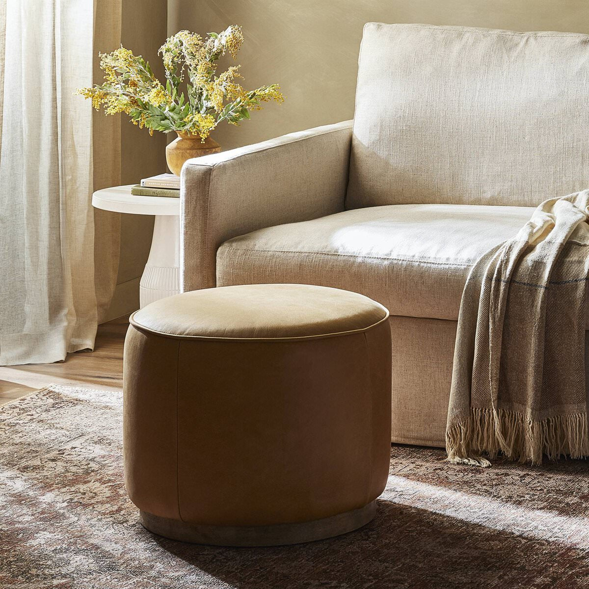 Four Hands Sinclair Round Ottoman in Palermo Butterscotch in a neutral living room