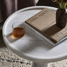 Close up of Four Hands Skylar End Table in Polished White Marble next to a chair