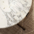 Close up of Four Hands Sophie End Table in Veined White Marble with a beige run in the background