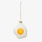 Glass sunny side up fried egg ornament on a white background