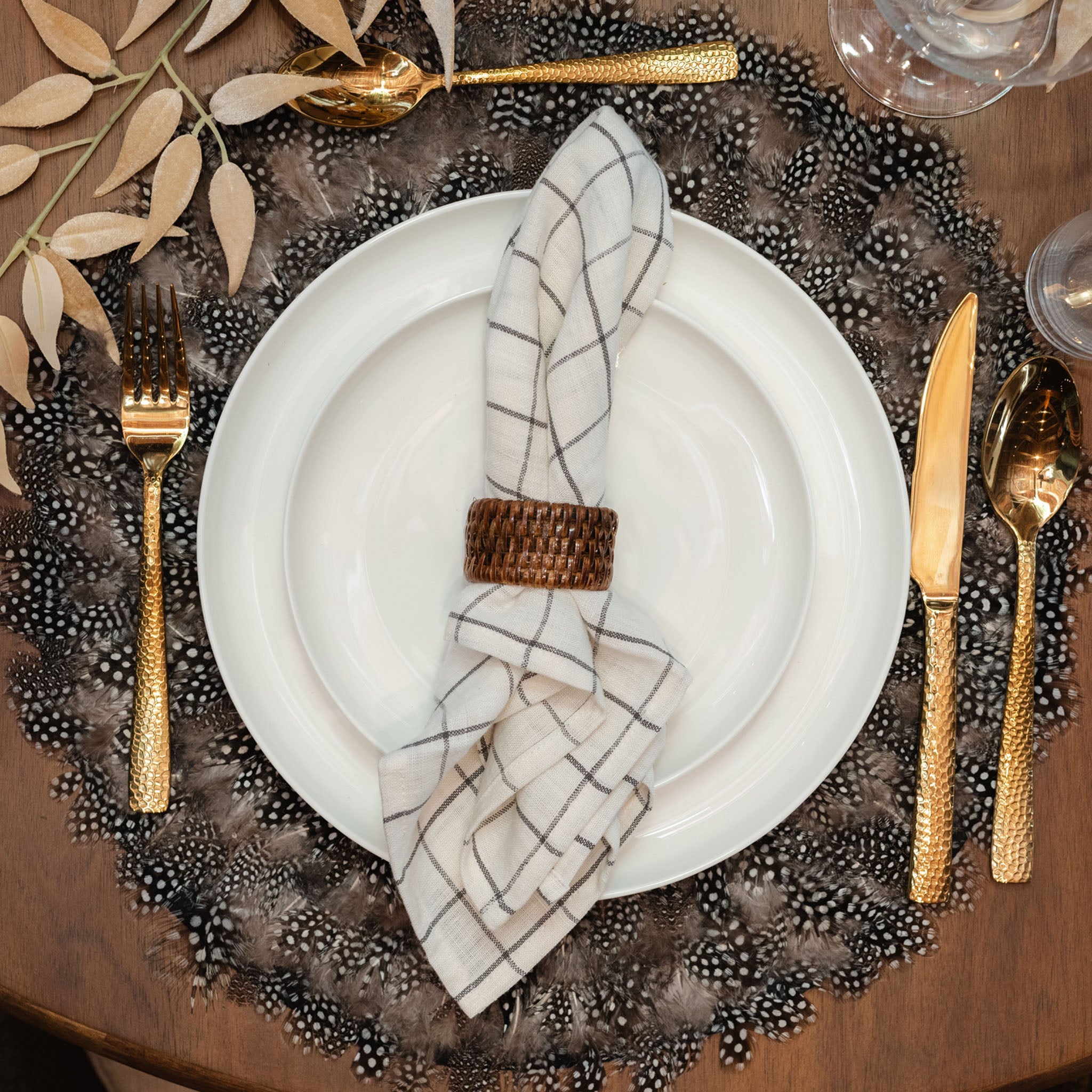 Table setting with feather placemat and white coupe dinner and salad plates stacked with a napkin on top 