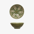 Green serving bowl with ornate white painted design inside on a white backgound