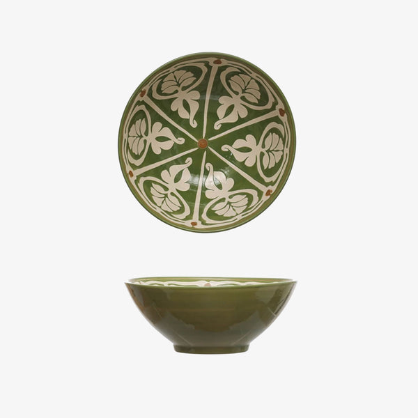 Green serving bowl with ornate white painted design inside on a white backgound