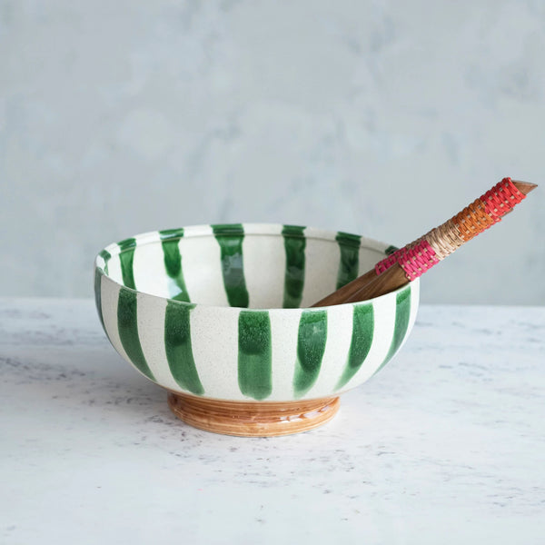 Green and white striped painted bowl with pedestal foot on a grey surface 