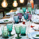 Table set outside with white plates and colorful tublers and glasses by la Rochere