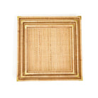 Stack of three square rattan trays with brass corners on a white background