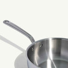 Close up of Made In Stainless Clad 3 qt. Saucier with Lid on a beige background at Addison West