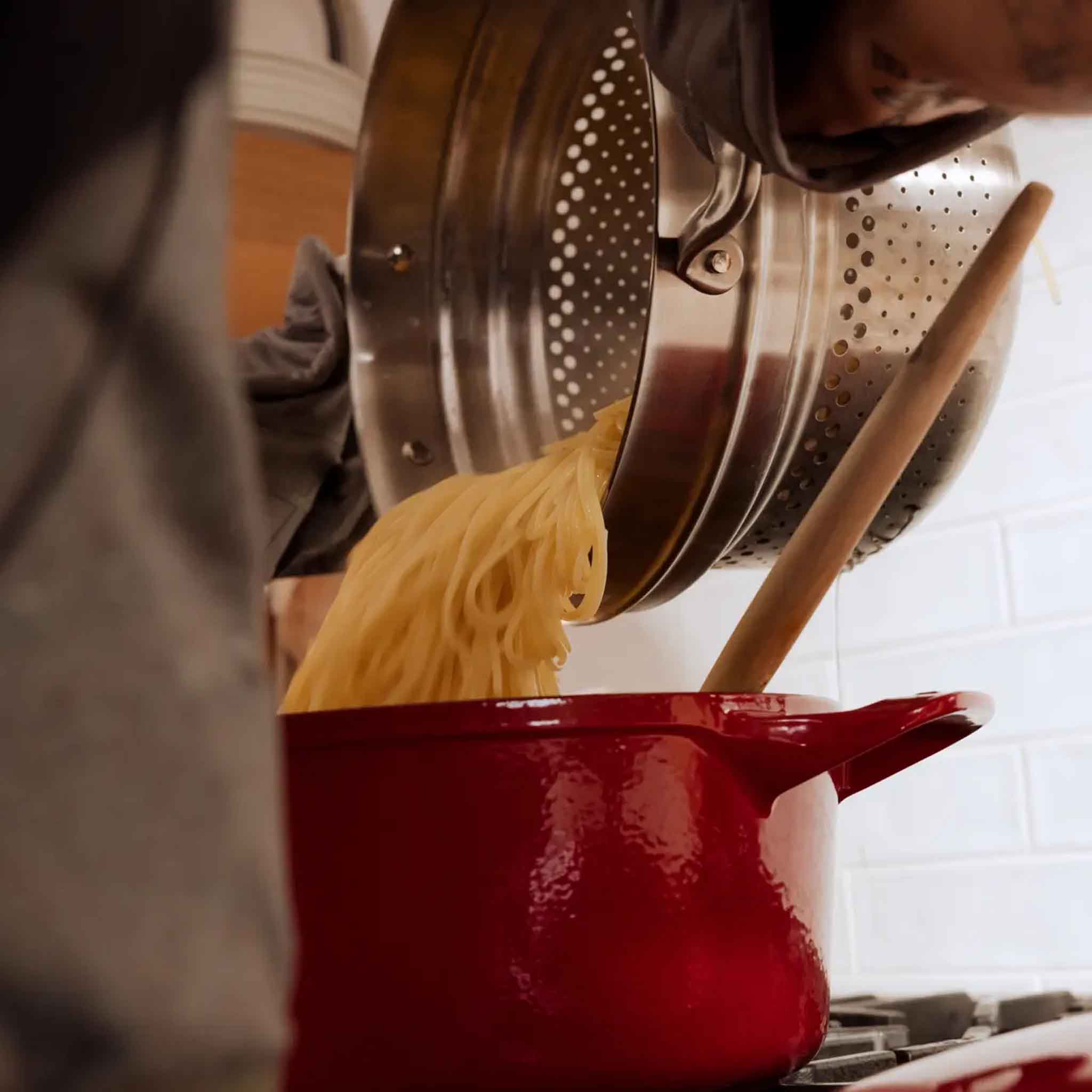 Made In Stainless Steel Pasta Insert pouring pasta into a serving dish at Addison West