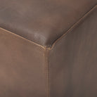 Close up of Minara 36" Square Brown Leather Wrapped w/Wood Base Ottoman on a white background