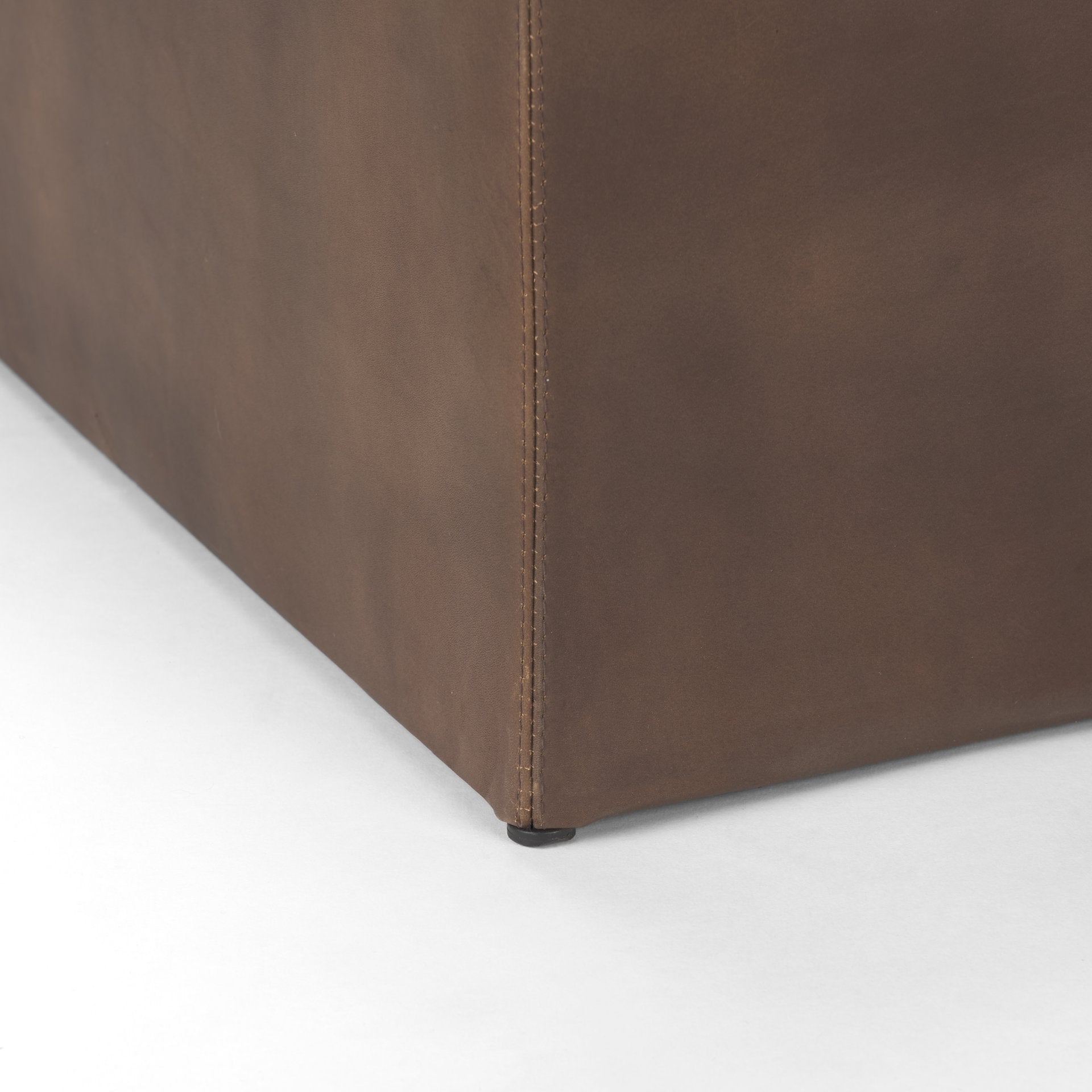 Close up of Minara 36" Square Brown Leather Wrapped w/Wood Base Ottoman on a white background