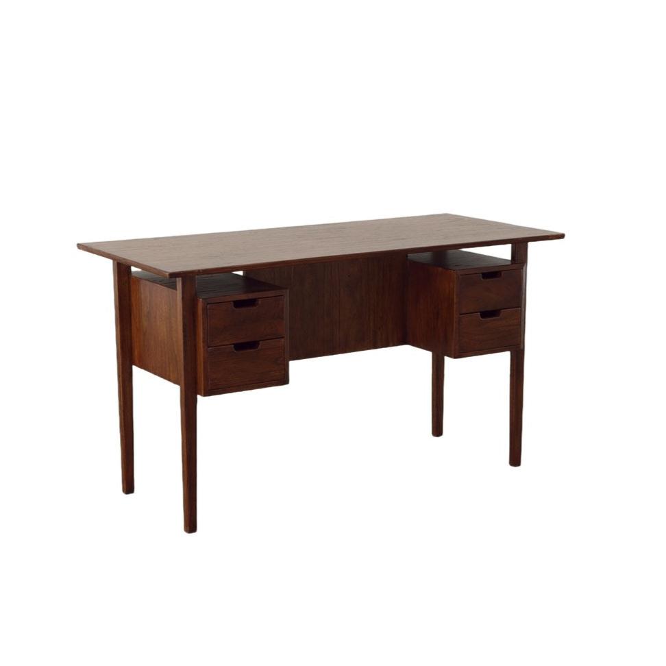 Dark wood desk with four drawers and mid century styling on a white background