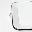 White enamel tray with black edge and handles on a white background