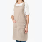 Model wearing Cross-Back Linen Apron in Natural Linen on a white backrgound