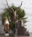 Resin wood toned Deer Head Mount on a white wood wall with a wreath around its head and a shelf with vintage books 