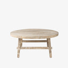 Whitewashed wood round coffee table with square dowel legs and bracing on a white background