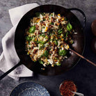 Smithey carbon steel wok with fried rice and linen napkin beside it on a grey counter