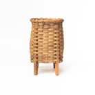 Hand woven rattan flower vase with oak feet on a white background