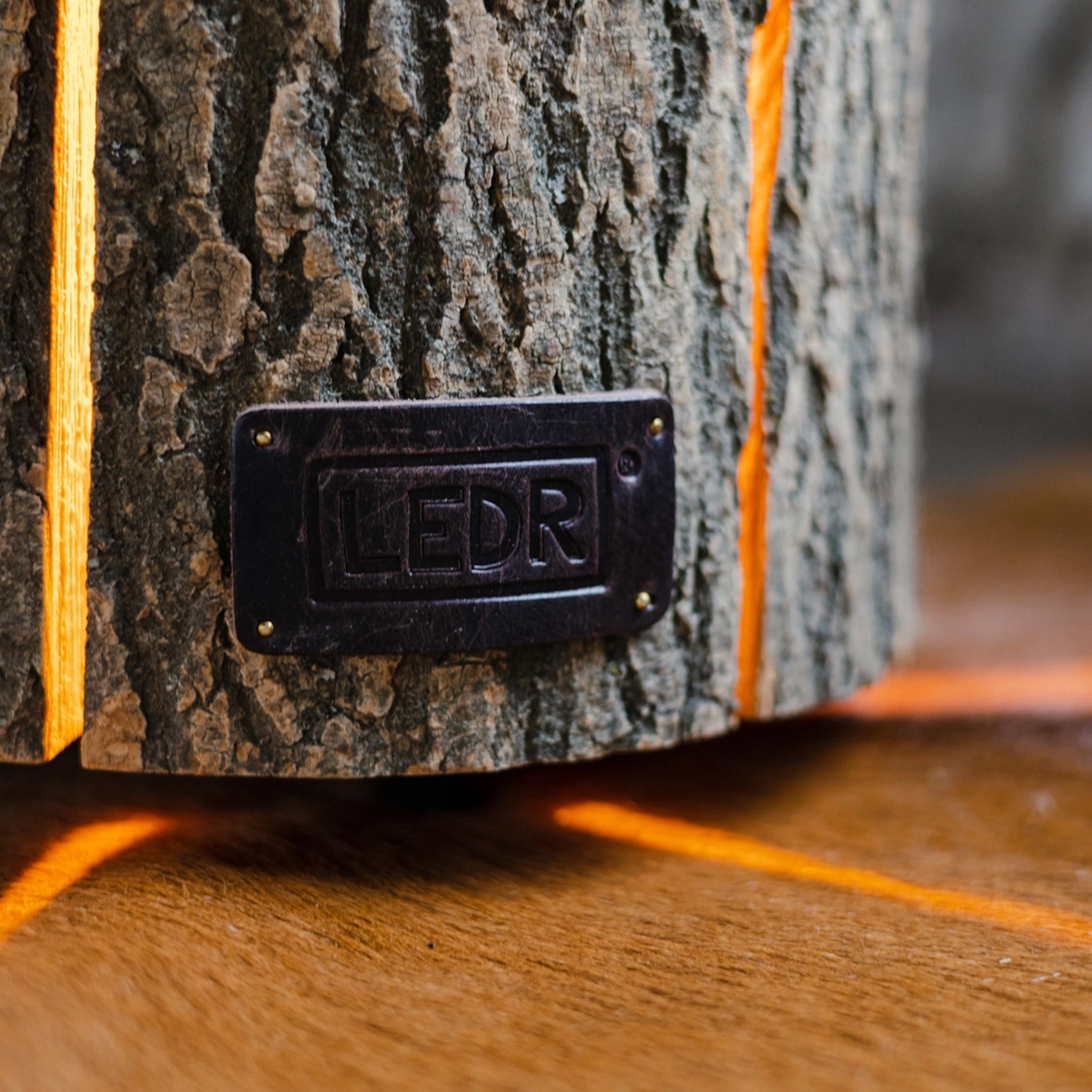 Close up of LEDR Medium Ash Wood Trunk Light with Leather Strap on a wood table at Addison West