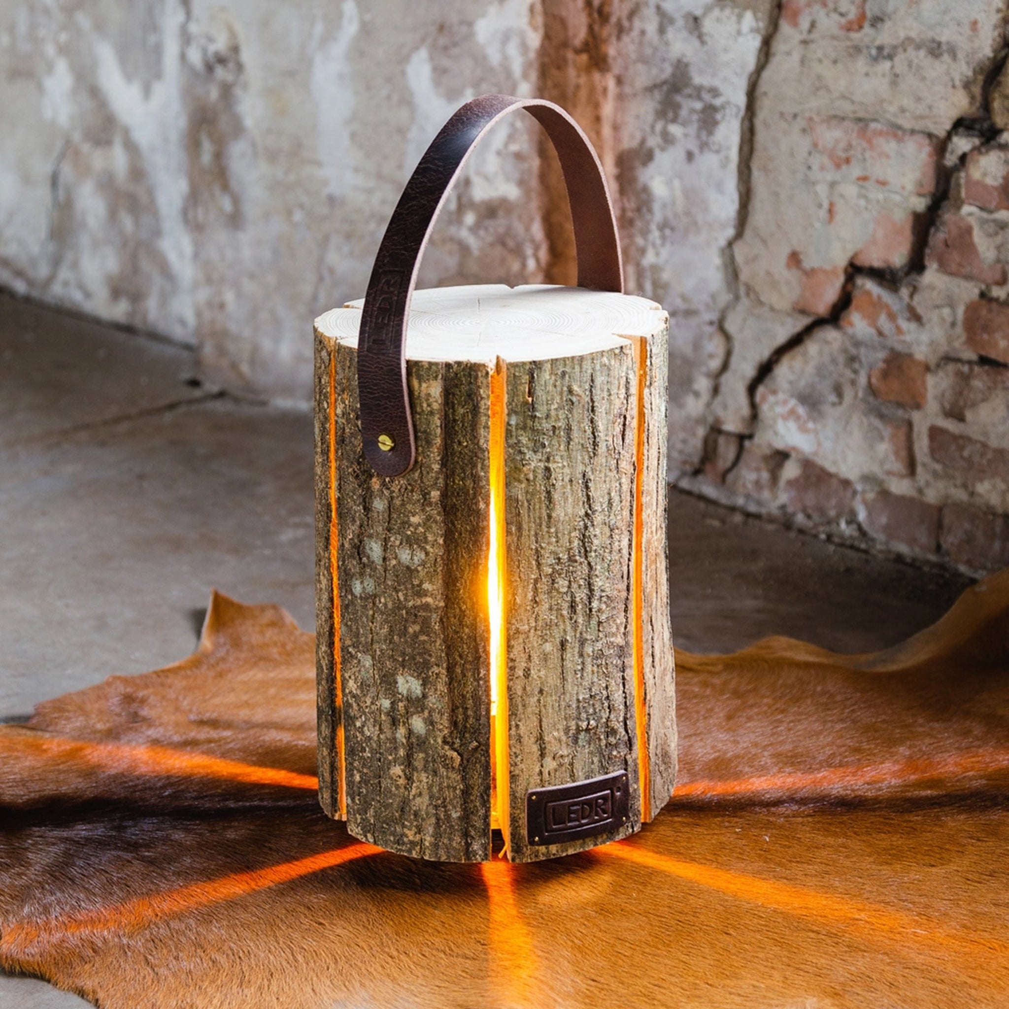 LEDR Medium Ash Wood Trunk Light with Leather Strap on a hide rug at Addison West