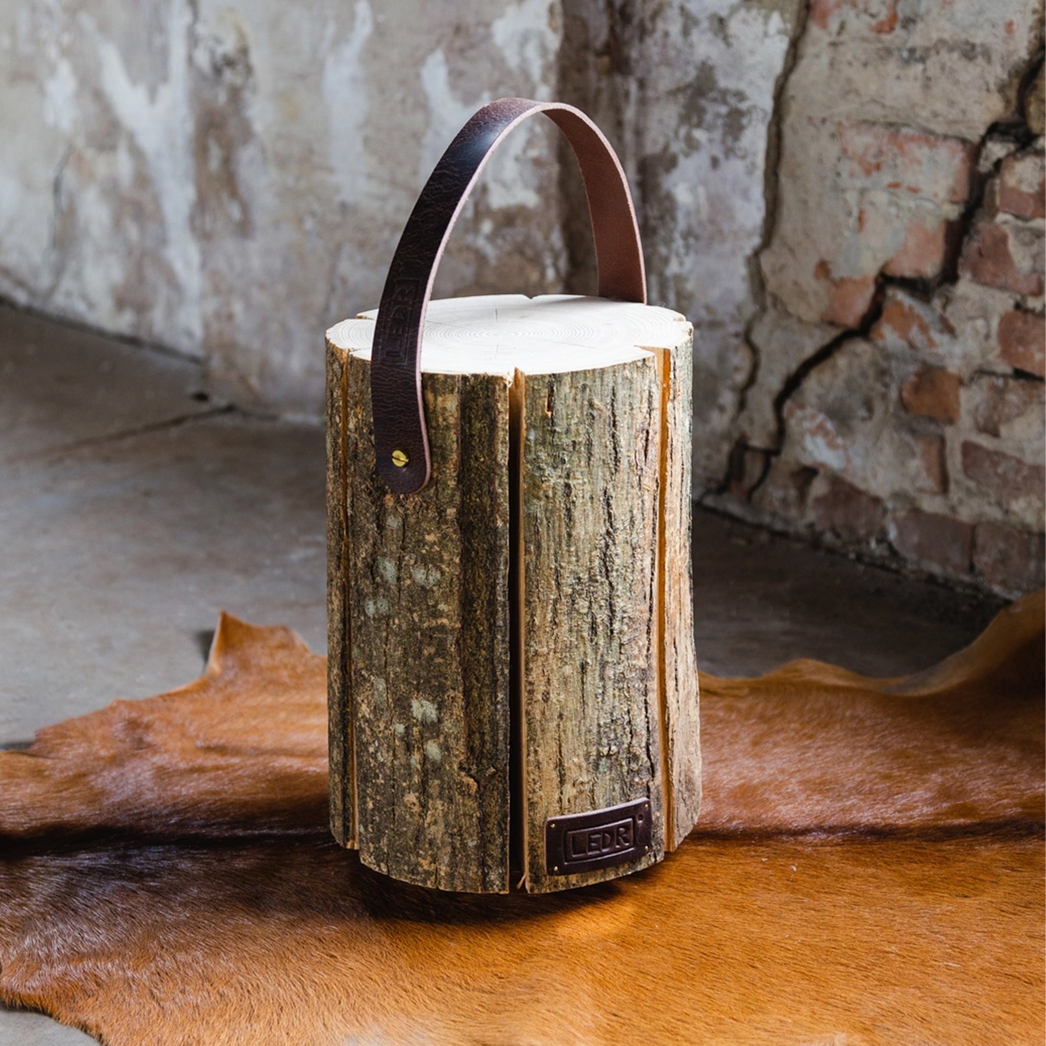 LEDR Medium Ash Wood Trunk Light with Leather Strap on a hide rug at Addison West