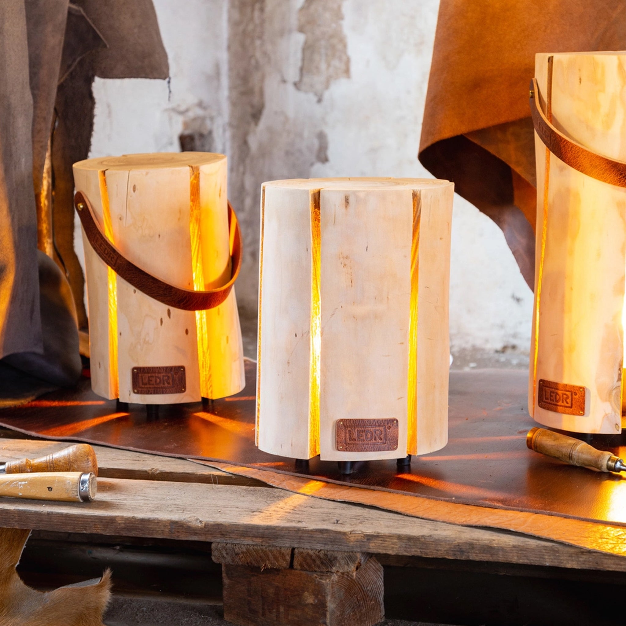 Large and Medium Cherry Trunk Light with Leather Strap on a wood table at Addison West