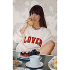 Model wearing Z Supply Oversized Lover Sweatshirt in Vanilla Ice driving juice at a breakfast table