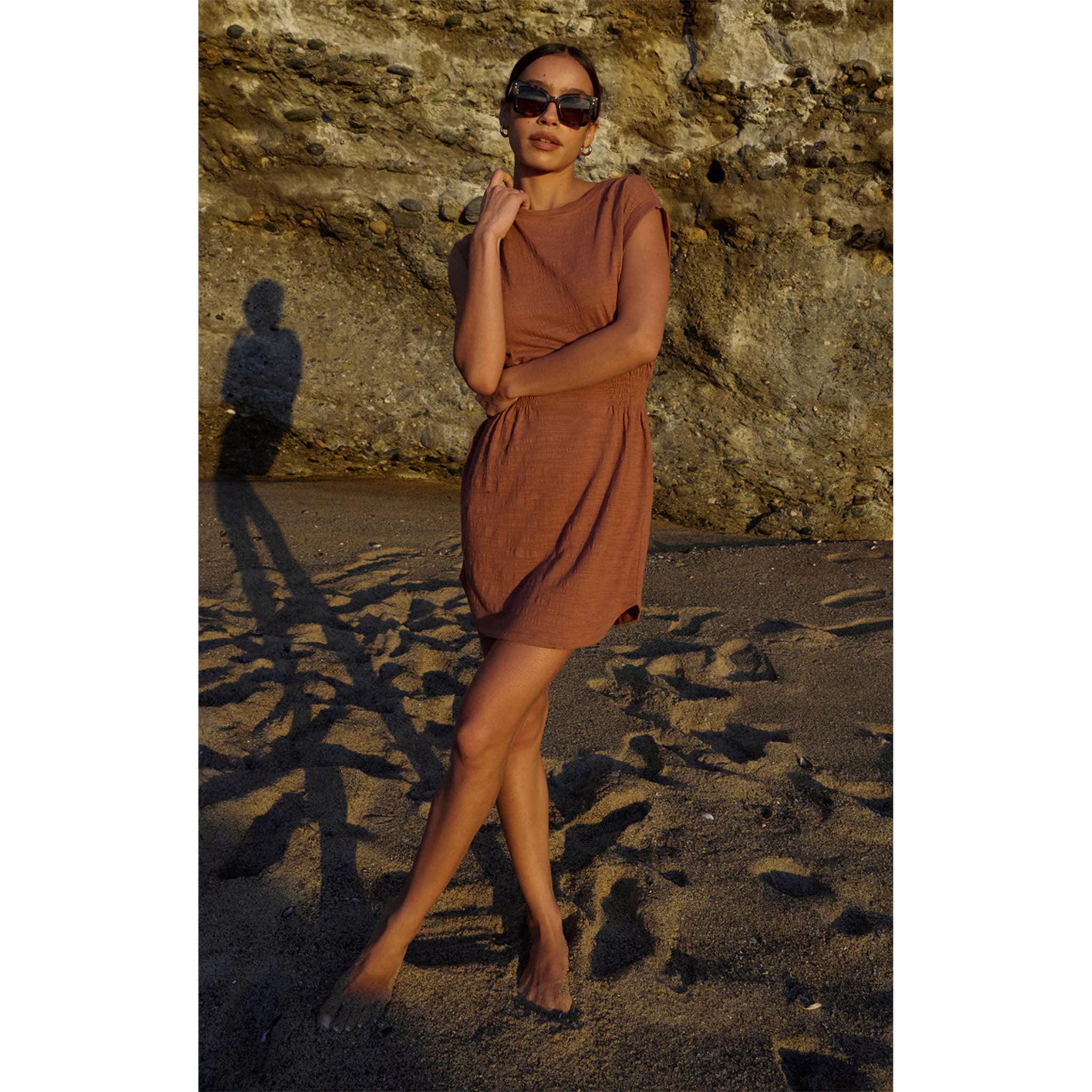 Model wearing Z Supply Rowan Textured Knit Dress in Bronzer on a beach with sunglasses