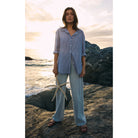 Model wearing Z Supply Seaport Striped Shirt in Sky Blue tucked in on a rock by the ocean