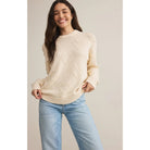 Model wearing Z Supply Sweet Thing Sweater in Sandstone with light blue jeans in front of a neutral backdrop