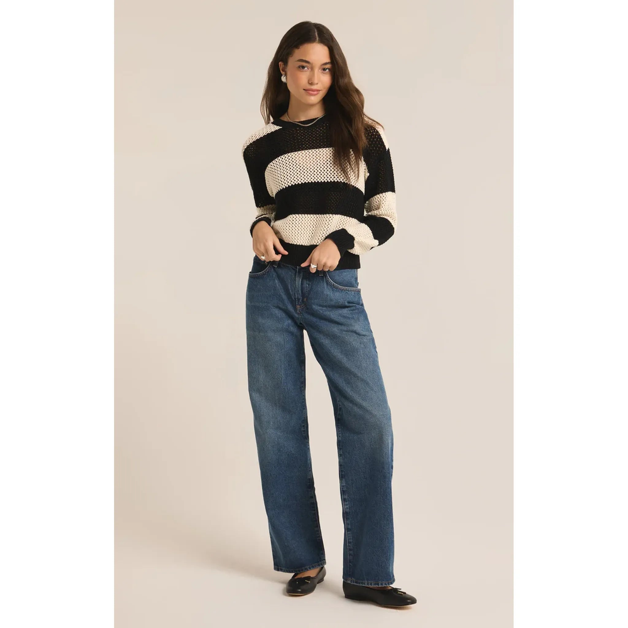 Model wearing wide leg jeans and Z Supply Broadbeach Stripe Sweater in Black in front of a white background