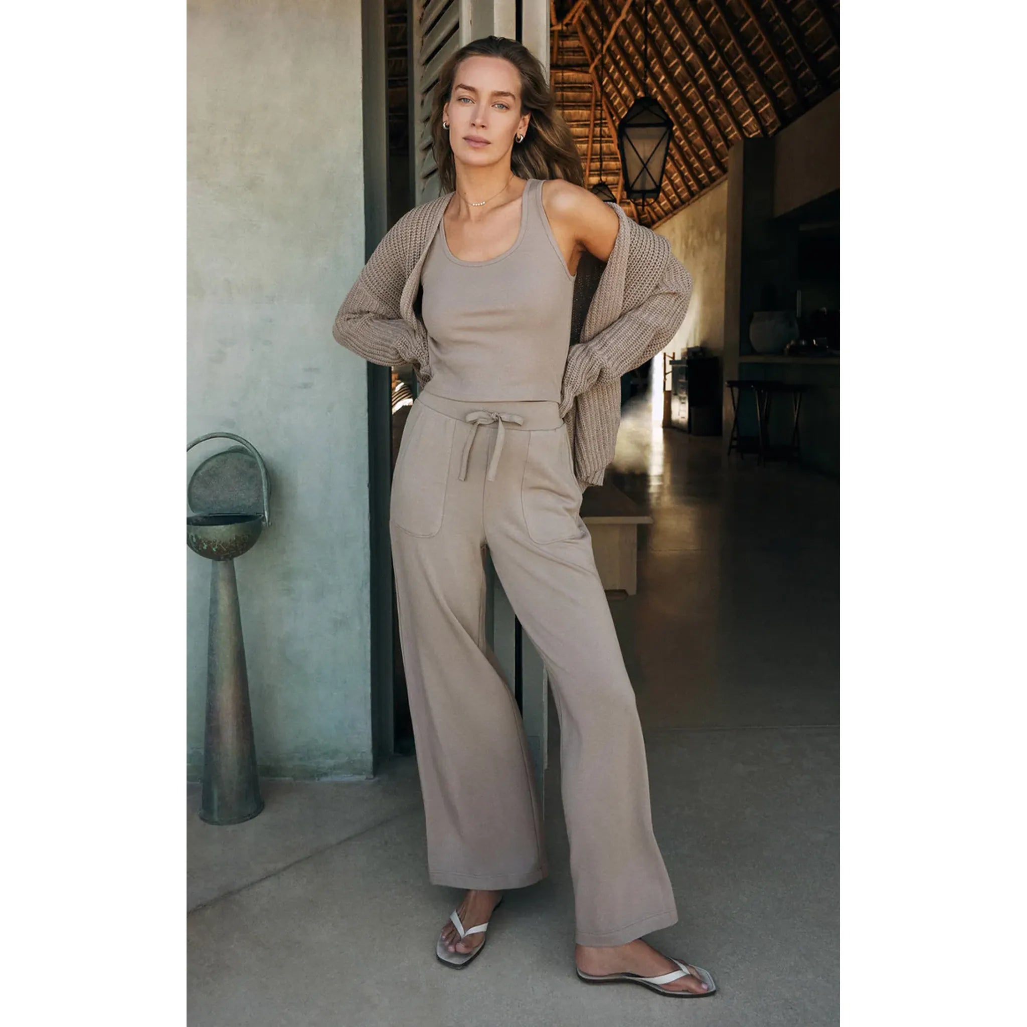 Model wearing Z Supply Layover Pant in Slate Grey with matching tank and sweater in front of a doorway 