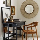 Ingrid Arm Chair in Teak against a beige background and brick floor at a black desk