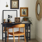 Ingrid Arm Chair in Teak against a beige background and brick floor at a black desk