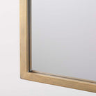 Arched top wall mirror with brushed gold finish on a white background