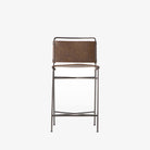 Four hands brand wharton counter stool with black iron frame and dark brown leather seat on a white background